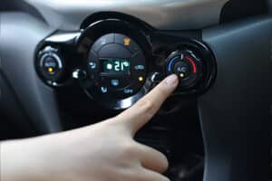 手指按下汽车空调及暖气系统的电源开关，开启车内空调的风扇。自动气候控制。